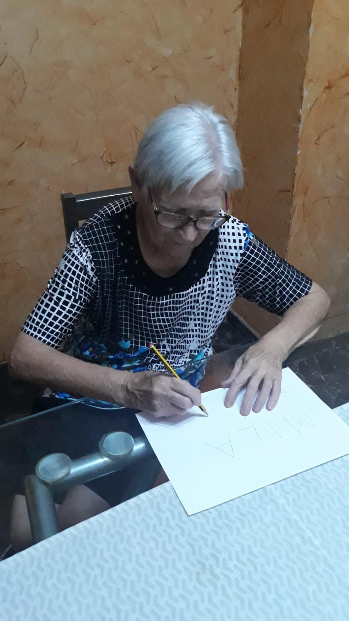 Milagros Boj escribiendo su nombre.
