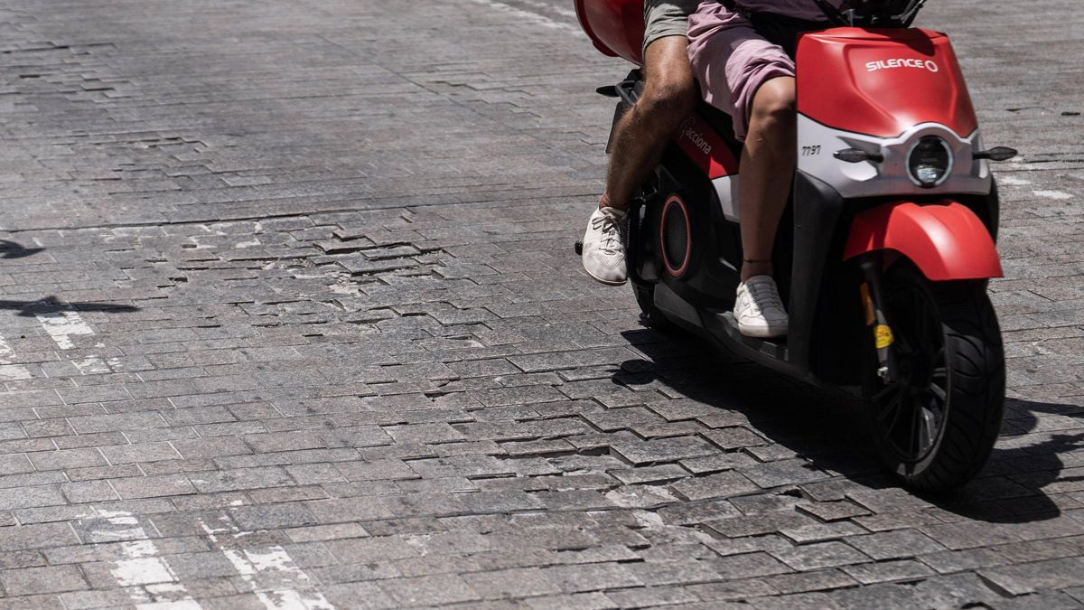 Una moto circula por un tramo con baches en la calle Pi i Margall, en Barcelona.