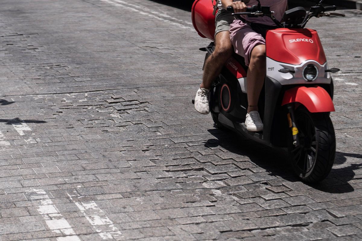 Una moto circula por un tramo con baches en la calle Pi i Margall, en Barcelona.