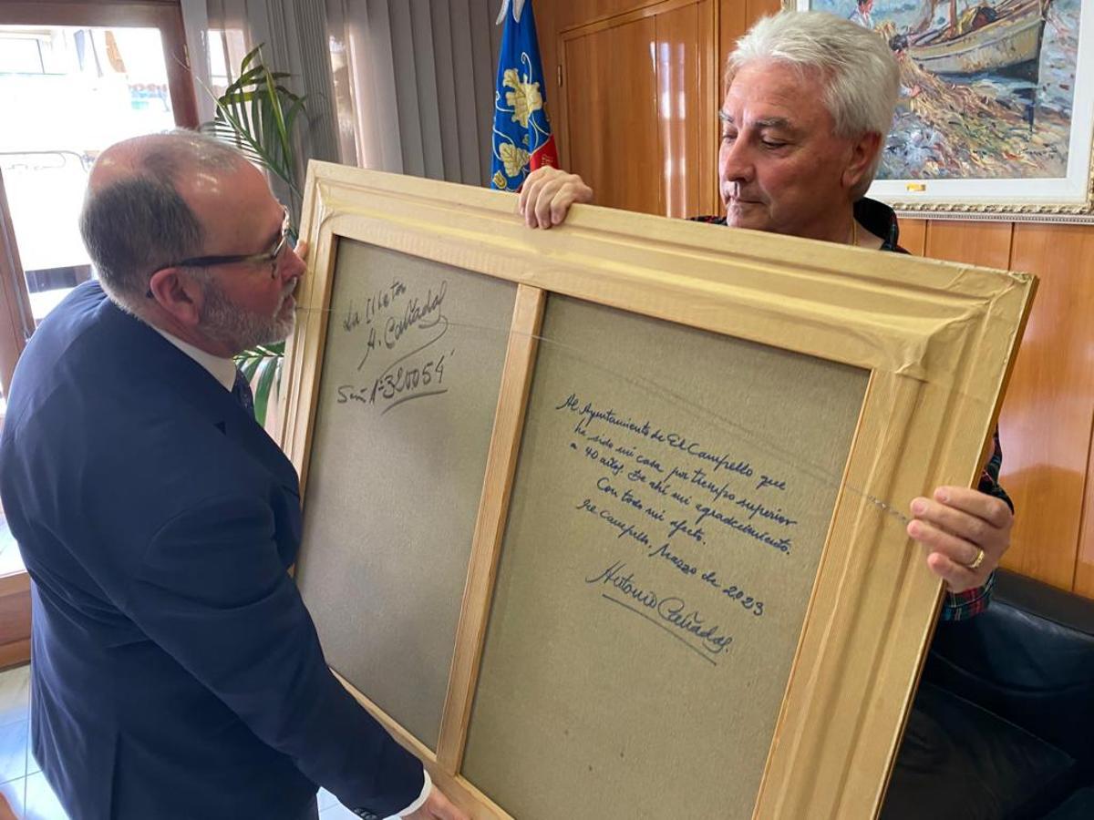 Cañadas muestra al alcalde la dedicatoria del reverso del cuadro donado