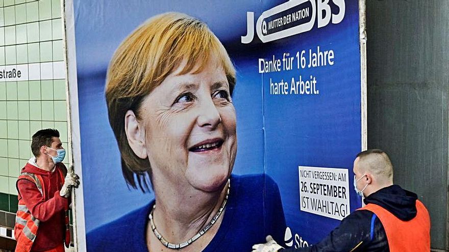 Operaris retirant un cartell d’Angela Merkel | REUTERS/FABIAN BIMMER