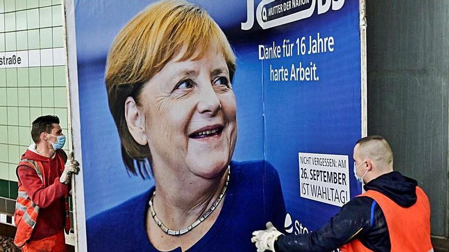 Operaris retirant un cartell d’Angela Merkel