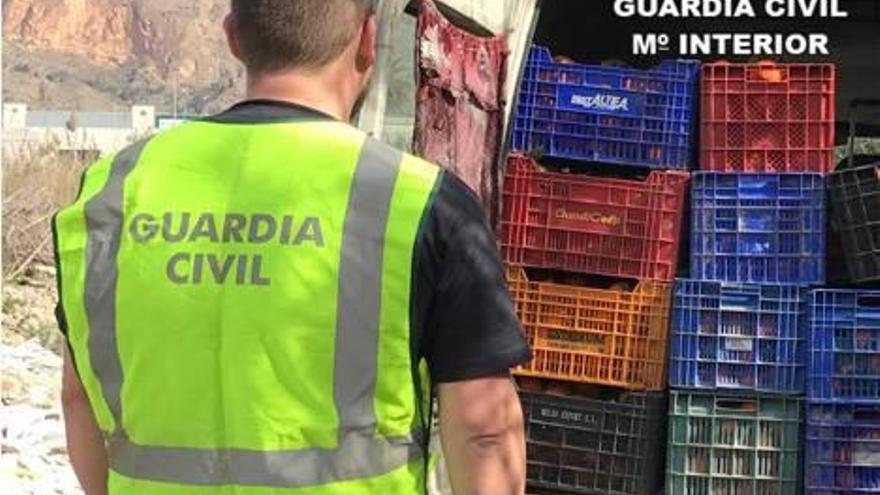 Un agente de la Guardia Civil observa el interior de una furgoneta incautada con fruta.