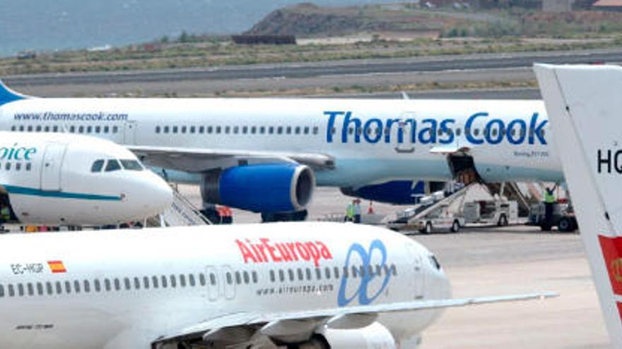 Varios aviones en la pista de un aeropuerto, entre ellos uno de Thomas Cook Airlines.