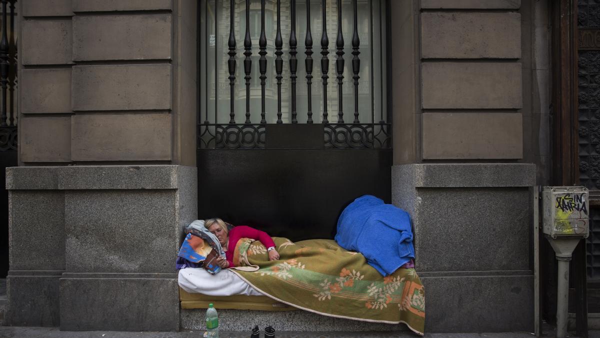 Una mujer sin hogar durmiendo en un portal en Barcelona.