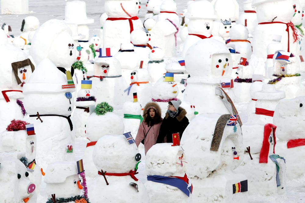 Una pareja camina entre muñecos de nieve en el río Songhua en China