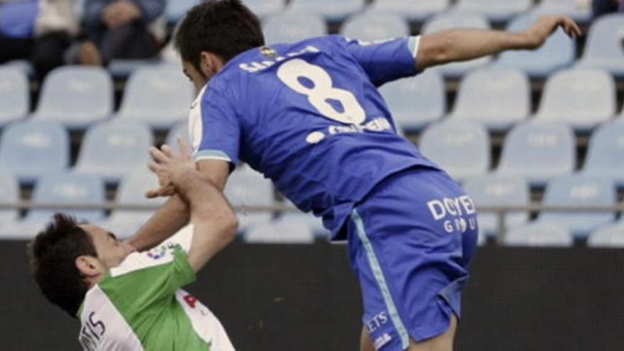 El jugador del Racing de Santander Pedro Munitis (i) intenta frenar una internada del centrocampista del Getafe Pablo Sarabia.