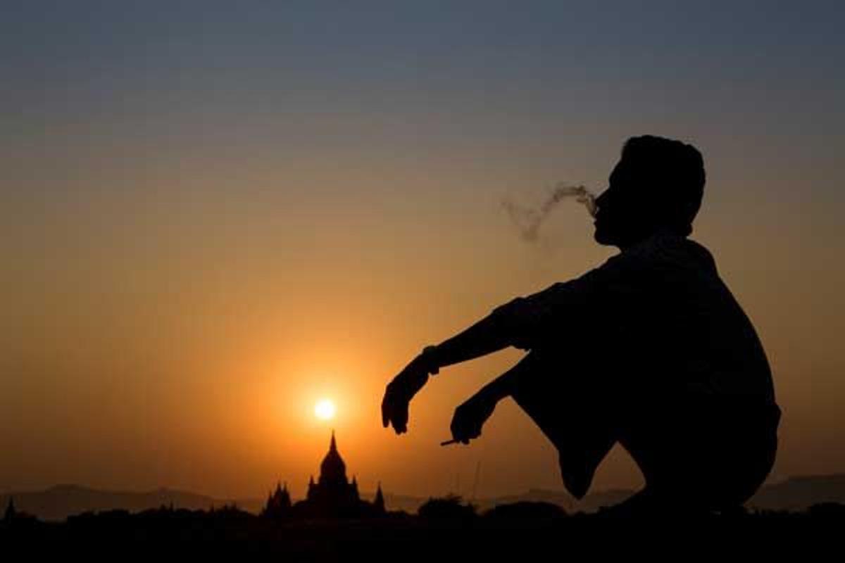 Silueta de un hombre fumando con los Templos de Bagan al fondo.