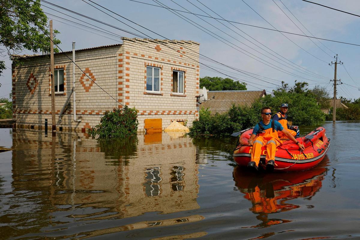 Los miembros del ministerio de emergencias de Rusia utilizan un bote inflable en un área inundada durante una operación de rescate tras el colapso de la presa de Nova Kakhovka.