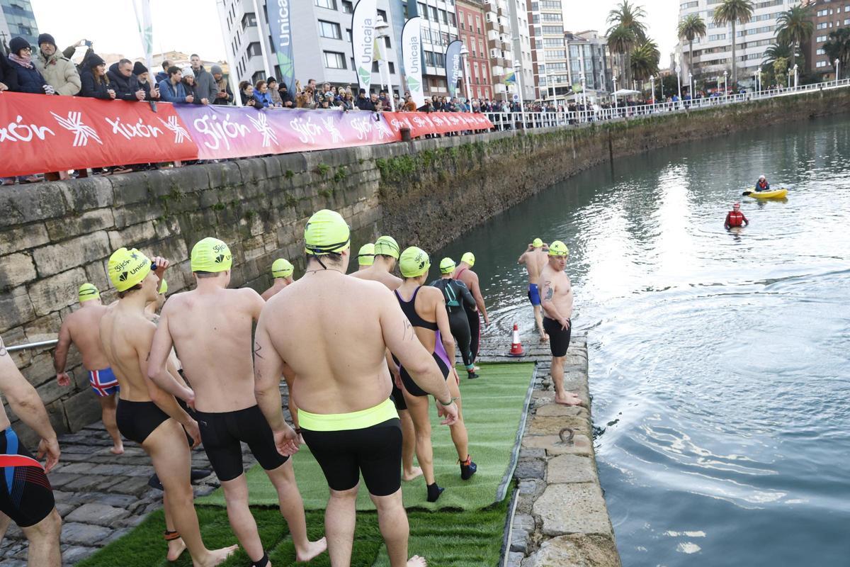 La travesía a nado de Navidad en Gijón congrega un año más a decenas de participantes (en imágenes)