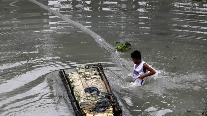 Un nen camina per un carrer inundat de Taguig City