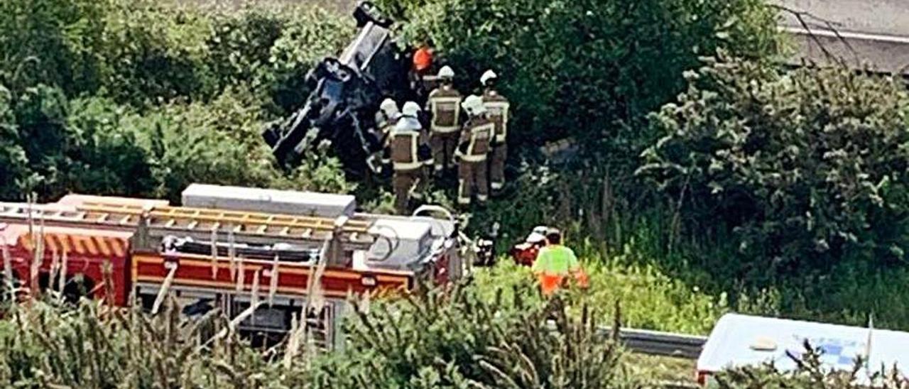 Los bomberos recuperando el vehículo del accidente, el 26 de mayo de 2019, junto a la autopista.