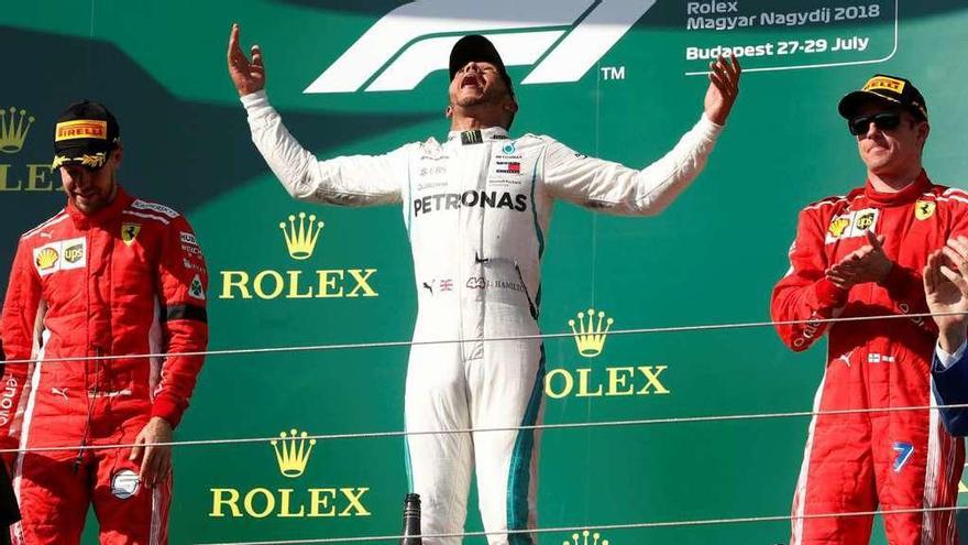 Hamilton celebra su victoria en lo más alto del podio del GP de Hungría lanzando al aire su trofeo de ganador.