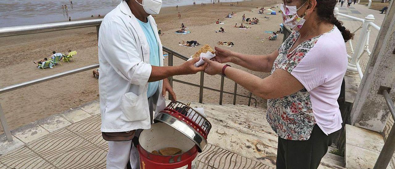 Guillermo Pelayo vende uno de sus barquillos a Ángela Cerro Barroso, ayer, en la playa de Salinas.