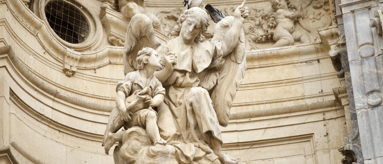 Palomas, este sábado sobre una estatua de la fachada de la Catedral de Murcia.