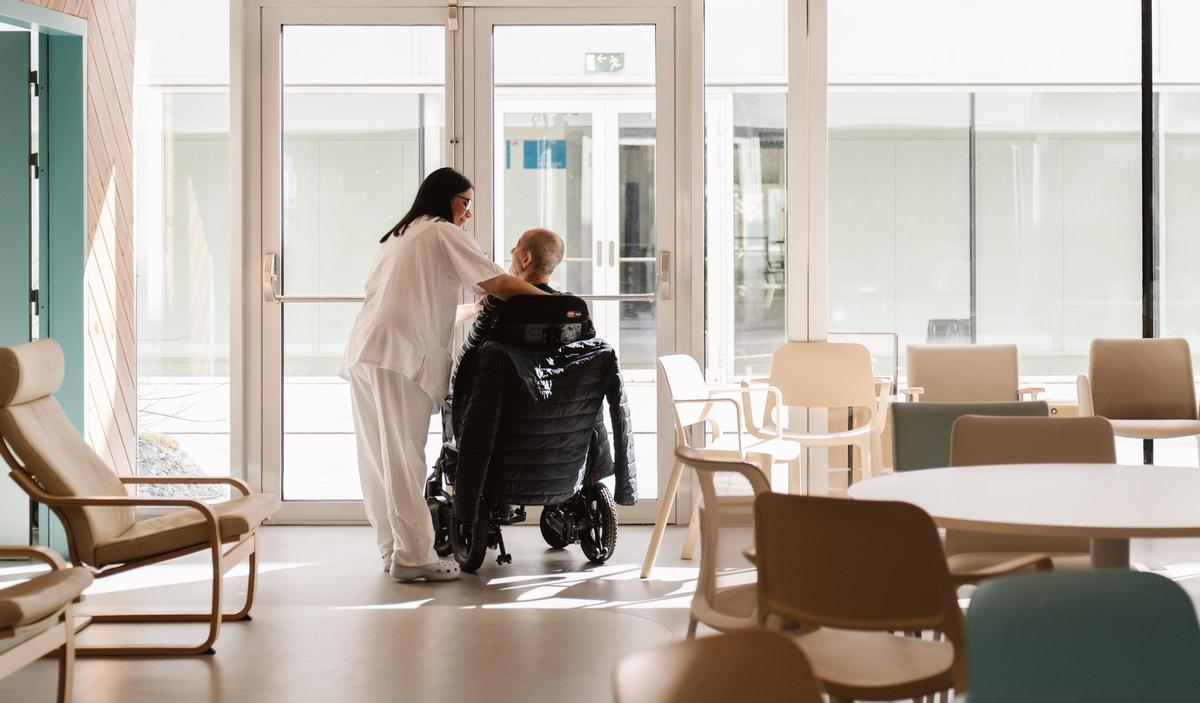 Una sanitaria y un paciente en el centro diurno de ELA