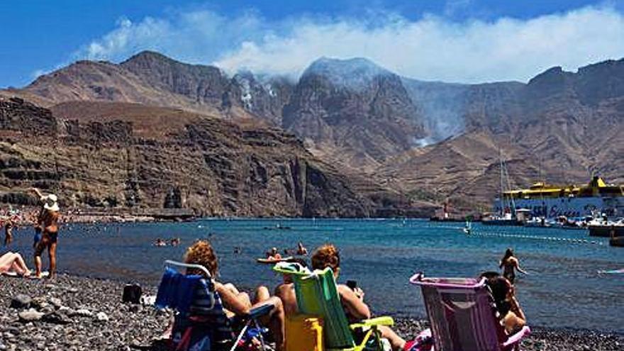 Bañistas en la playa de Agaete (Gran Canaria) observan el humo del incendio.