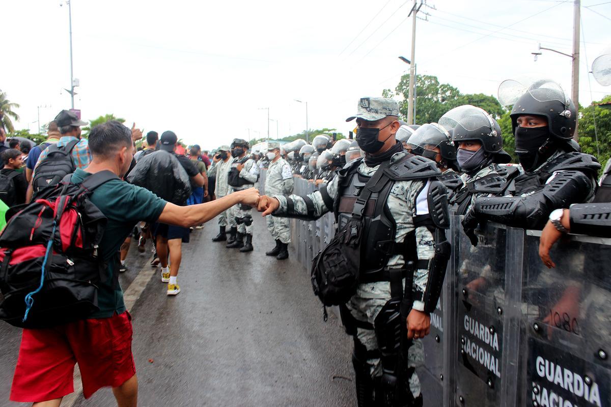 Una persona migrante saluda a un miembro de la Guardia Nacional durante su camino hoy, hacia la frontera norte, en el estado de Chiapas (México).