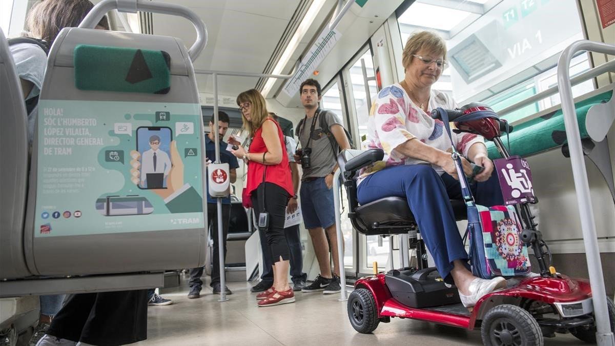 Una usuario del Tram accede al tranvía de Barcelona con su 'scooter', esta mañana