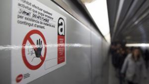 Un cartel avisa de la presencia de amianto tras el revestimiento de las paredes del pasillo de enlace en la estación de metro de Catalunya, en una imagen de archivo.