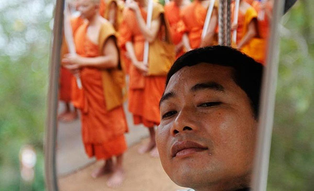 Un conductor cambodjà s’afaita mentre uns monjos budistes passen en una marxa per la muntanya d’Udon durant la cerimònia del Dia de Vesak, per celebrar el naixement i la mort de Buda.