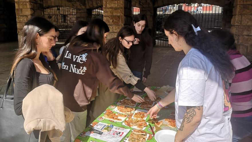 Adriana González, a la derecha, ofrece un trozo de pizza a varias estudiantes de la Facultad. | Ángel González