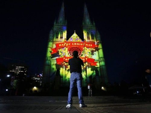 Man photographs St Mary's Cathedral in Sydney as it is illuminated by a 75-metre-high projected display titled "Lights of Christmas"