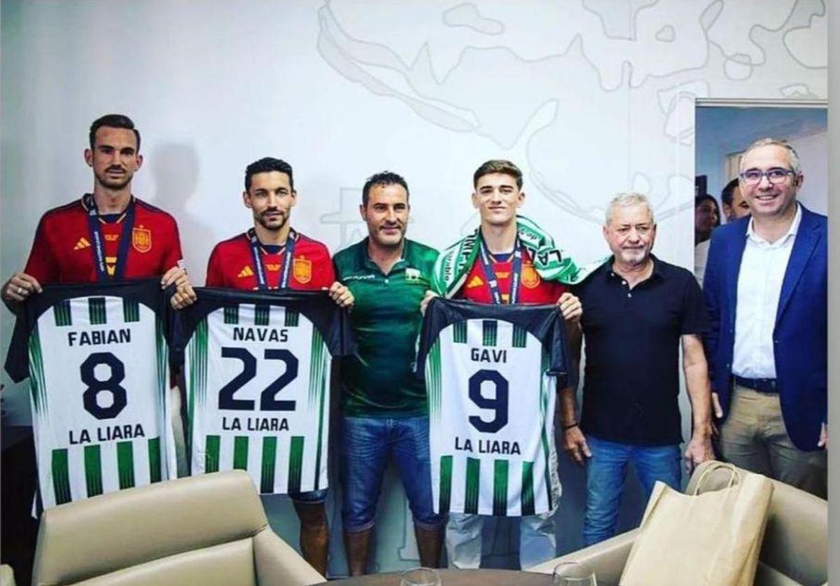 Fabían, Jesús Navas y Gavi reciben la camiseta del centenario de La Liara. A la derecha Campón (presidente de La Liara) y el alcalde de Los Palacios.