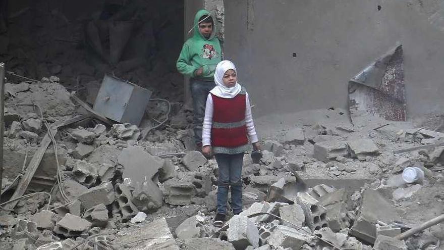 Dos menores sirios entre las ruinas de un edificio en Guta.