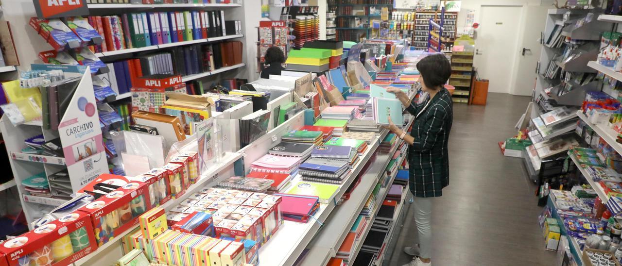 Una mujer en una librería con material escolar, para el que muchos concellos ofrecen ayudas.