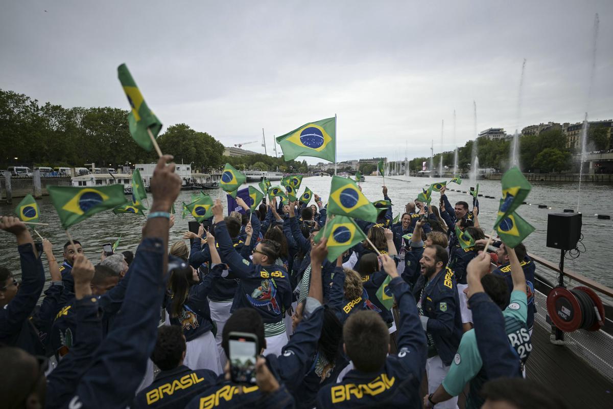 Atletas de la delegación de Brasil ondean banderas brasileñas mientras navegan en un barco por el río Sena durante la ceremonia de apertura de los Juegos Olímpicos de Verano 2024 en París
