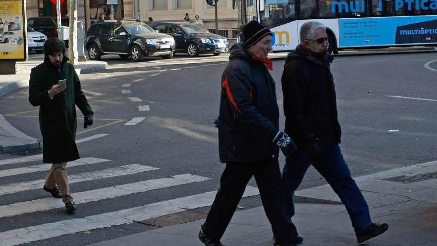 Varias personas caminan por la ciudad, abrigadas para protegerse del frío.