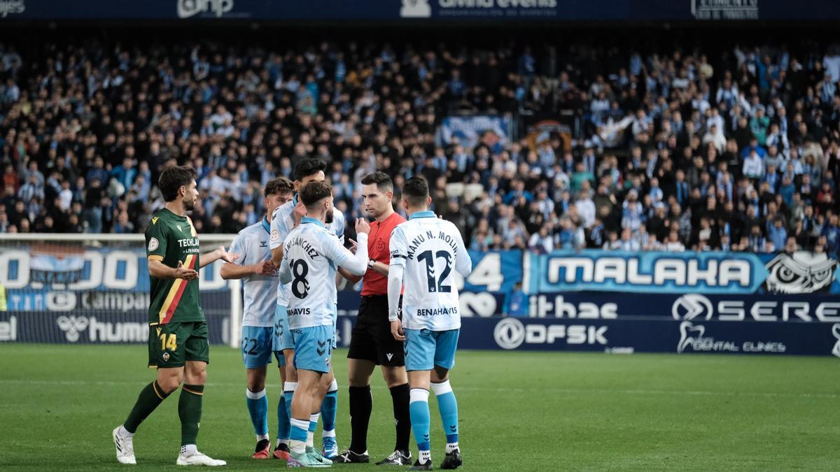 Los jugadores del Málaga CF conversan con el árbitro.