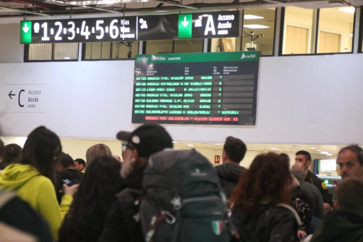 Panel informativo anunciado una cancelación de un tren delante la aglomeración de pasajeros a la estación de Sants.