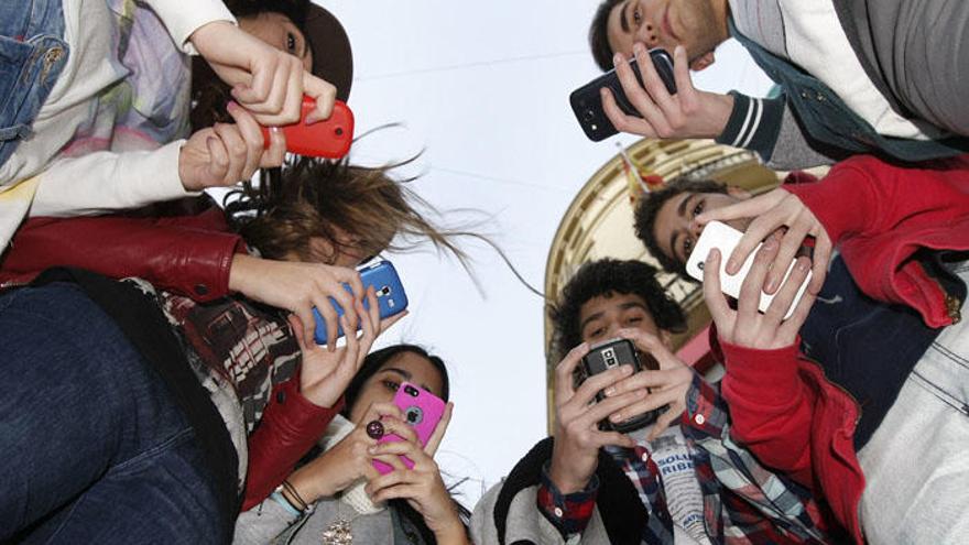 Un grupo de jóvenes usa el móvil en la calle Larios.