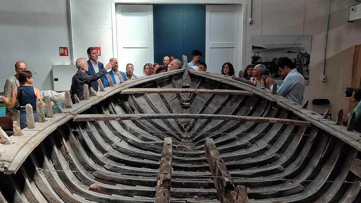 La visita inaugural de los nuevos espacios del Museo Massó, con el conselleiro de Cultura, José López Campos (a la izq.), y con el pecio original de la xeiteira «Marina». | Santos Álvarez
