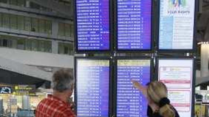 Turistas consultan los vuelos en el aeropuerto.