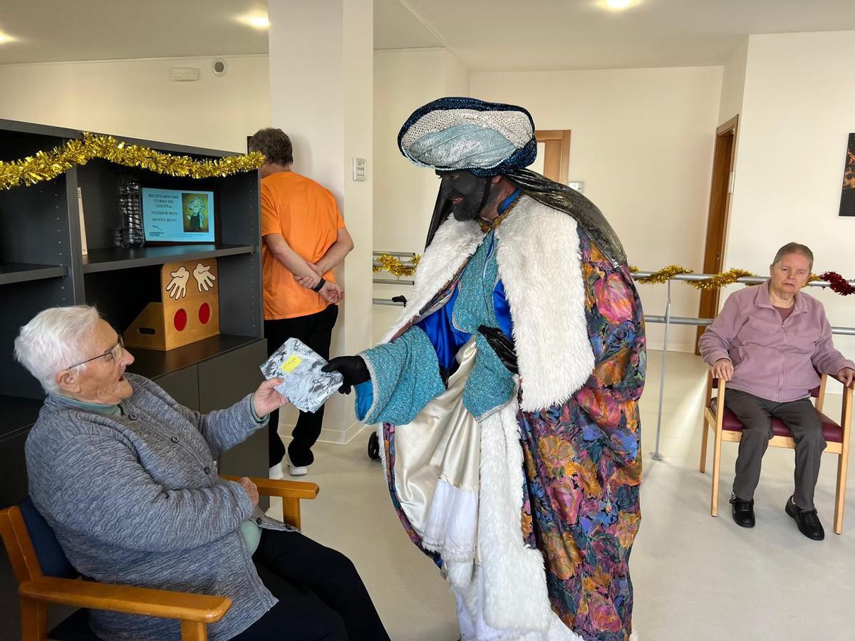 El Rey Baltasar entregando un regalo a una usuaria del centro de día de Cabana.