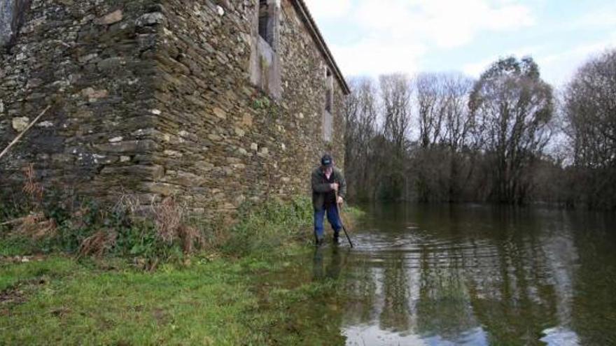 Ramón Carril, ayer, junto a su vivienda, deshabitada, inundada por la crecida en Beigondo (Santiso).  // Bernabé/Gutier