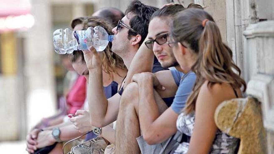 Turistas a la sombra bebiendo agua en Palma.