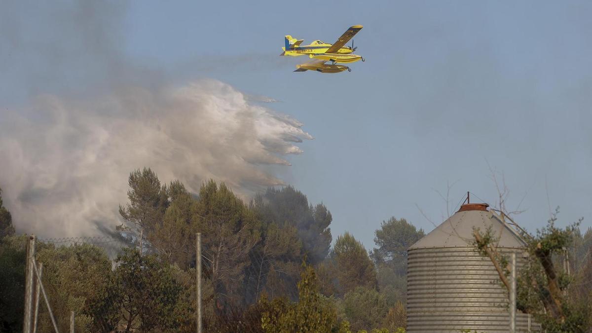 Un avión lanza una descarga de agua sobre la zona afectada por el incendio