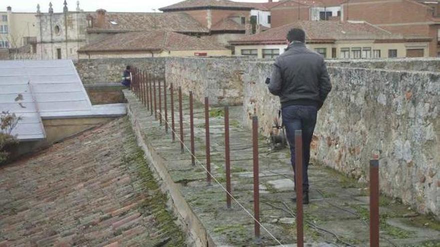 Operarios trabajan en la instalación de una nueva barandilla de seguridad en el adarve del Alcázar. Foto