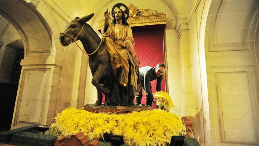 El florista Jerónimo Tripiana engalana con flores hechas de palma blanca el paso de Jesús Triunfante en la basílica de Santa María, ayer por la tarde.  | MATÍAS SEGARRA
