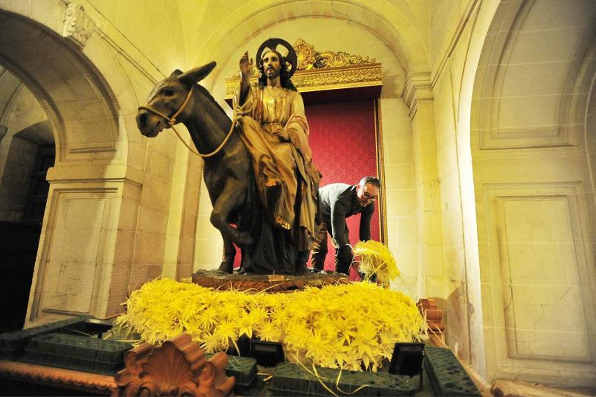 El florista Jerónimo Tripiana engalana con flores hechas de palma blanca el paso de Jesús Triunfante en la basílica de Santa María, ayer por la tarde.  | MATÍAS SEGARRA