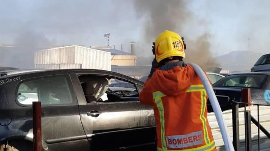 Un bombero sofoca las llamas en el incendio de un desguace de coches de Massamagrell.