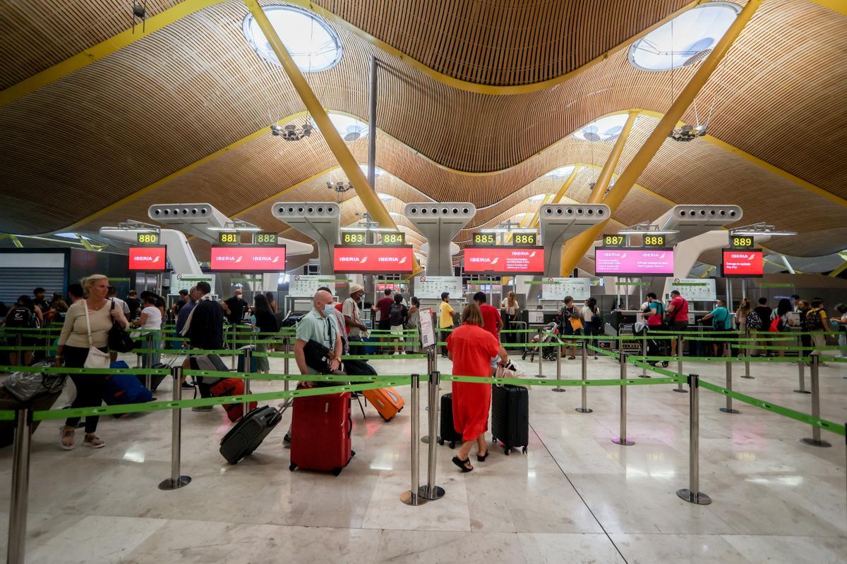 Varios pasajeros esperan para obtener sus tarjetas de embarque y facturar su equipaje en el día en que ha dado comienzo una huelga de los tripulantes de cabina de Iberia Express, en la T4 del Aeropuerto Adolfo Suárez Madrid-Barajas, a 28 de agosto de 2022