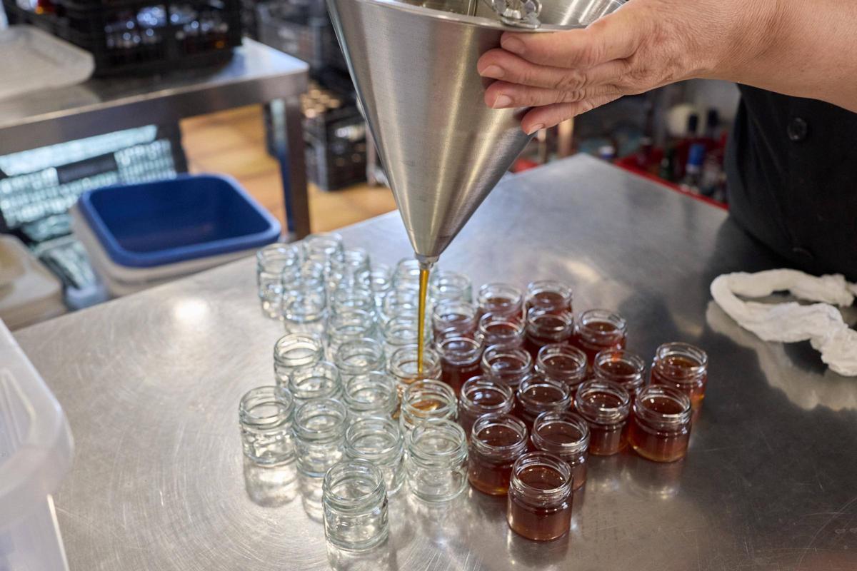 Treballadaor del Museu emplenant petits pots amb mel.