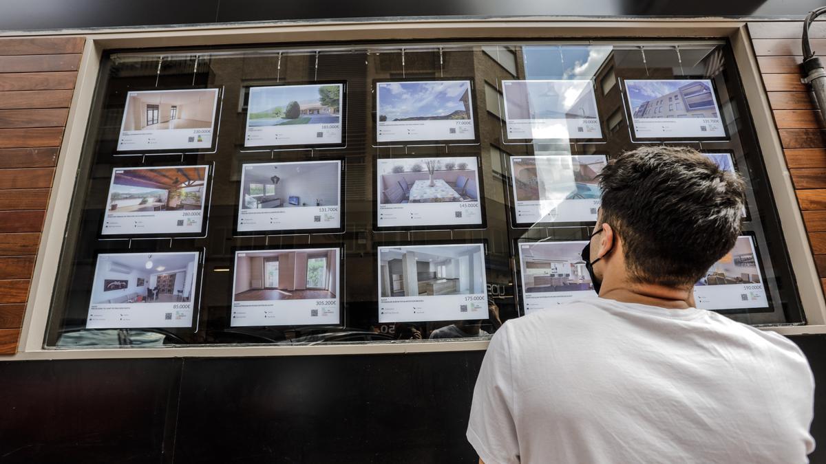 Un joven mira el escaparate de una inmobiliaria en la provincia.