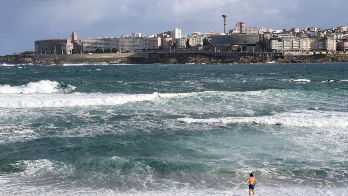 Una persona en traje de baño en la playa coruñesa de Riazor, este pasado sábado, con aviso por olas.