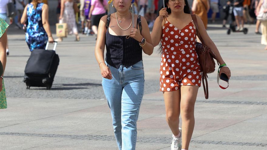 Archivo - Dos personas usan un paraguas para protegerse del sol, a 30 de julio de 2024, en Madrid (España).